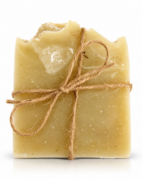 A rectangular bar of handmade soap in a light tan or oatmeal color, wrapped with a rustic brown jute twine bow, set against a plain white background.