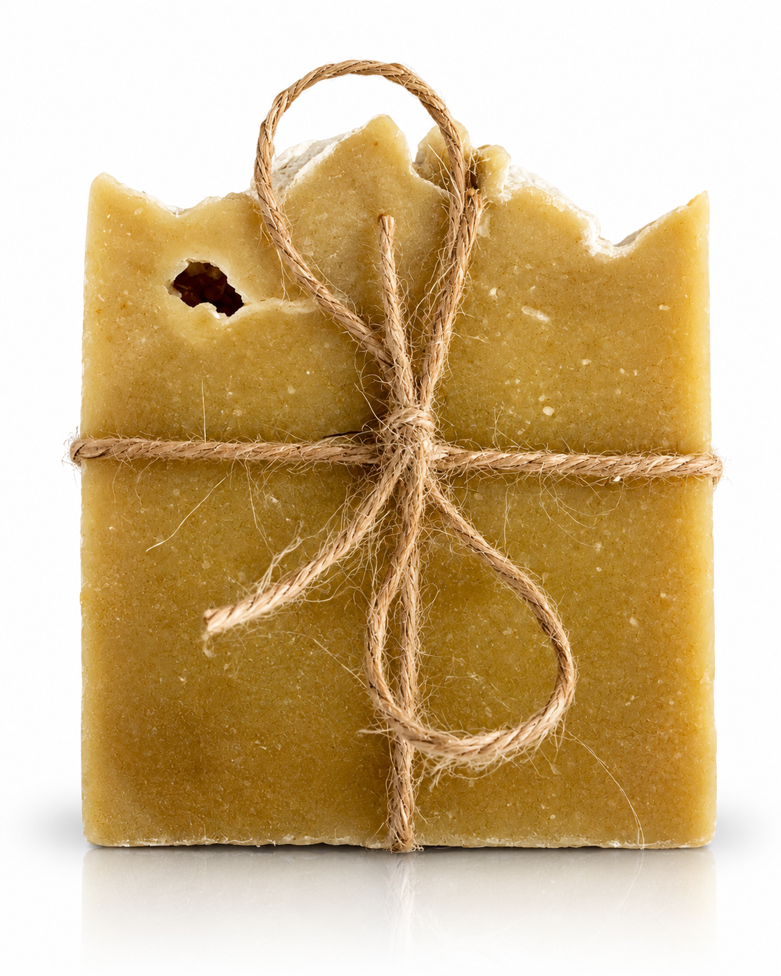 A rustic handmade soap bar in a warm mustard-yellow color, tied with a simple brown jute twine bow on a clean white background.