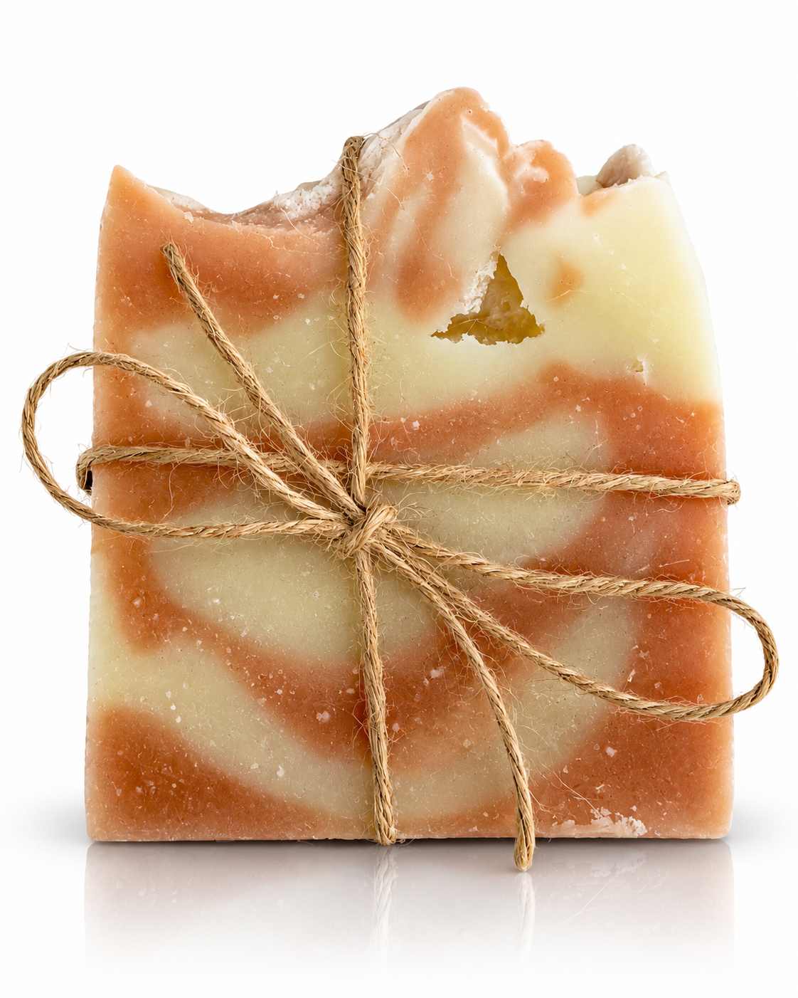 A handmade rectangular bar of soap with a swirled pattern of light cream and warm tan, wrapped in natural jute twine and tied in a bow, on a white background.
